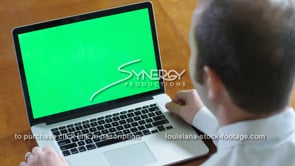 1850 Millennial business man watches video laptop green screen